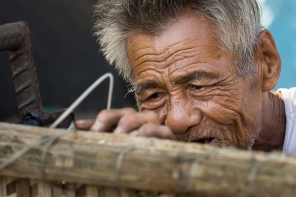 Un vieil homme vietnamien réparant des bateaux