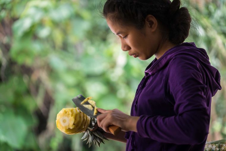 Portrait d'une jeune fille vietnamienne découpant un ananas